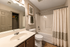 Elegant bathroom with a sleek white vanity, modern fixtures, and a pristine bathtub accented by a stylish shower curtain.