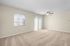 Inviting living room with plush carpeting, large windows for natural light, and a modern ceiling fan.