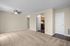 Inviting open-concept living room with plush carpeting, modern ceiling fan, and a view into a cozy kitchen with wooden cabinetry.