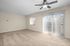 Spacious apartment with plush carpeted living area, stylish ceiling fan, and a modern kitchen with stainless steel appliances.