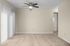 Bright and spacious living area with plush carpeting and modern ceiling fan, featuring large windows and neutral tones.