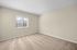 Bright, sunlit bedroom with soft beige carpet and neutral walls, perfect for customization.