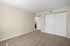 Bright, spacious second bedroom with plush carpet, neutral walls, and ample closet space, leading to a bathroom.