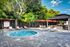 Serene outdoor area with inviting jacuzzi, surrounded by lush greenery and modern lounge chairs, perfect for relaxing.