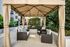 Elegant outdoor gazebo with comfortable wicker seating, surrounded by lush greenery, offering a tranquil escape in a modern apartment setting.
