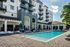 Luxurious apartment complex with a pristine outdoor pool, surrounded by modern architecture and stylish lounge chairs.