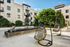 Chic apartment courtyard featuring modern hanging chairs, lush greenery, and serene water feature, perfect for relaxation and enjoyment.