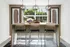 Bright dining area with modern bar stools and contemporary lighting, set against large windows revealing lush greenery outside.