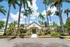 Inviting apartment complex entrance surrounded by lush palm trees and vibrant landscaping under a bright blue sky.