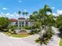 Tropical paradise apartment complex with lush palm trees and vibrant foliage, featuring elegant architecture under a clear blue sky.