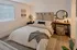 Inviting bedroom with elegant decor, featuring a cozy bed, stylish wall art, and a chic vanity with a round mirror.