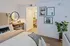 Charming bedroom with stylish decor, featuring a comfortable bed, wooden desk with modern lighting, framed artwork, and lush indoor plant, creating a cozy and inviting atmosphere.