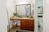 Elegant bathroom featuring a granite countertop with rich wood cabinetry, stylish plant decor, and a large illuminated mirror creating a welcoming ambiance.