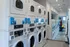 Modern apartment complex laundry room featuring state-of-the-art washers and dryers with digital controls, sleek design, and ample folding space.