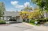 Charming apartment community with a welcoming entrance, lush greenery, and a well-maintained drive-up area under a clear blue sky.