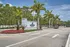 Inviting entrance to River North Apartments framed by lush palm trees and vibrant flowerbeds under a clear blue sky.