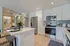 Modern kitchen with sleek stainless steel appliances, elegant white cabinetry, and a chic breakfast bar adorned with fresh orchids.