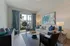 Inviting living room with elegant decor, featuring a cozy sofa, abstract artwork, and bright natural light from large windows overlooking a lush garden.