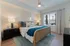 Bright and inviting bedroom with stylish decor, featuring a cozy bed, elegant nightstands, and a large window allowing natural light.