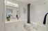 Elegant bathroom featuring a modern design with a sleek vanity, decorative wall art, and inviting bathtub with a chic shower curtain.