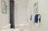 Bright and modern bathroom with elegant tile design, stylish artwork, and plush towels creating a serene oasis.