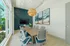 Modern conference room featuring elegant wooden table, stylish rolling chairs, large windows with outdoor view, decorative ocean-themed art, and contemporary pendant lighting.