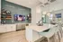 Elegant modern kitchen with a sleek island, designer pendant lights, and a wall-mounted TV, perfect for entertaining.