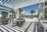 Luxurious outdoor pool area with stylish seating, palm trees, and modern architecture under a clear blue sky.