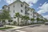 Modern apartment complex surrounded by lush palm trees, showcasing stylish balconies and a serene residential atmosphere.