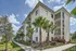 Contemporary apartment building with lush palm trees and vibrant landscaping under a bright blue sky.