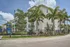 Bright and modern apartment building surrounded by lush palm trees and a colorful playground, offering a perfect blend of tranquility and family-friendly amenities.