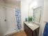 Modern bathroom with granite countertop, sleek dark wood cabinetry, vibrant blue decor, and a chic shower curtain.