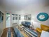 Contemporary living room with abundant natural light, featuring a cozy blue sofa, vibrant artwork, and a stylish rug enhancing the space.