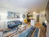 Modern open-concept living space with stylish decor, featuring a cozy blue sofa, vibrant artwork, and a sleek kitchen area.
