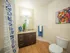 Modern bathroom with elegant hardwood floors, stylish granite countertop, and vibrant wall art, perfect for a contemporary home.