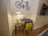 Contemporary study nook with a chic desk, elegant lamp, and wall-mounted bicycle art, perfect for a modern apartment vibe.