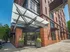 Contemporary urban apartment building entrance with sleek glass canopy and vibrant brick facade.