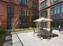 Modern apartment courtyard with stylish outdoor seating, sleek brick facade, and ambient string lights for a cozy atmosphere.