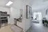Bright and modern apartment kitchen leading to a cozy living area with stylish decor and large windows.