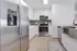 Modern kitchen featuring sleek stainless steel appliances, elegant white cabinetry, and pristine hardwood flooring.