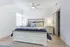Bright and inviting bedroom with elegant wooden furniture, a cozy king-size bed adorned with colorful pillows, and soft natural light enhancing the serene atmosphere.
