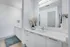 Modern bathroom with sleek white cabinetry, stylish countertop, large mirror, and elegant decor for a luxurious touch.