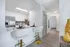 Modern kitchen with sleek white cabinetry and stainless steel appliances, featuring a cozy dining area with stylish bar stools and elegant table settings.