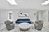 Modern lounge area featuring elegant marble flooring, a chic blue sofa, two stylish grey chairs, and contemporary artwork.