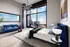 Luxurious modern bedroom featuring floor-to-ceiling windows with breathtaking city views, elegant blue sofa, and stylish decor.
