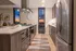 Contemporary kitchen with sleek stainless steel appliances, warm wood cabinetry, and a stunning sunset view through the window.