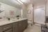 Modern bathroom with elegant dual sinks, sleek cabinetry, a large mirror, and a spacious walk-in shower.