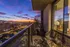 Luxurious apartment balcony offering stunning cityscape views at sunset, with modern outdoor seating and stylish decor.