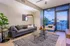 Modern living room with sleek gray couch, stylish decor, and panoramic city views through expansive windows.