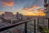 Breathtaking urban skyline view from a modern apartment balcony at sunset, featuring vibrant skies and a bustling cityscape.